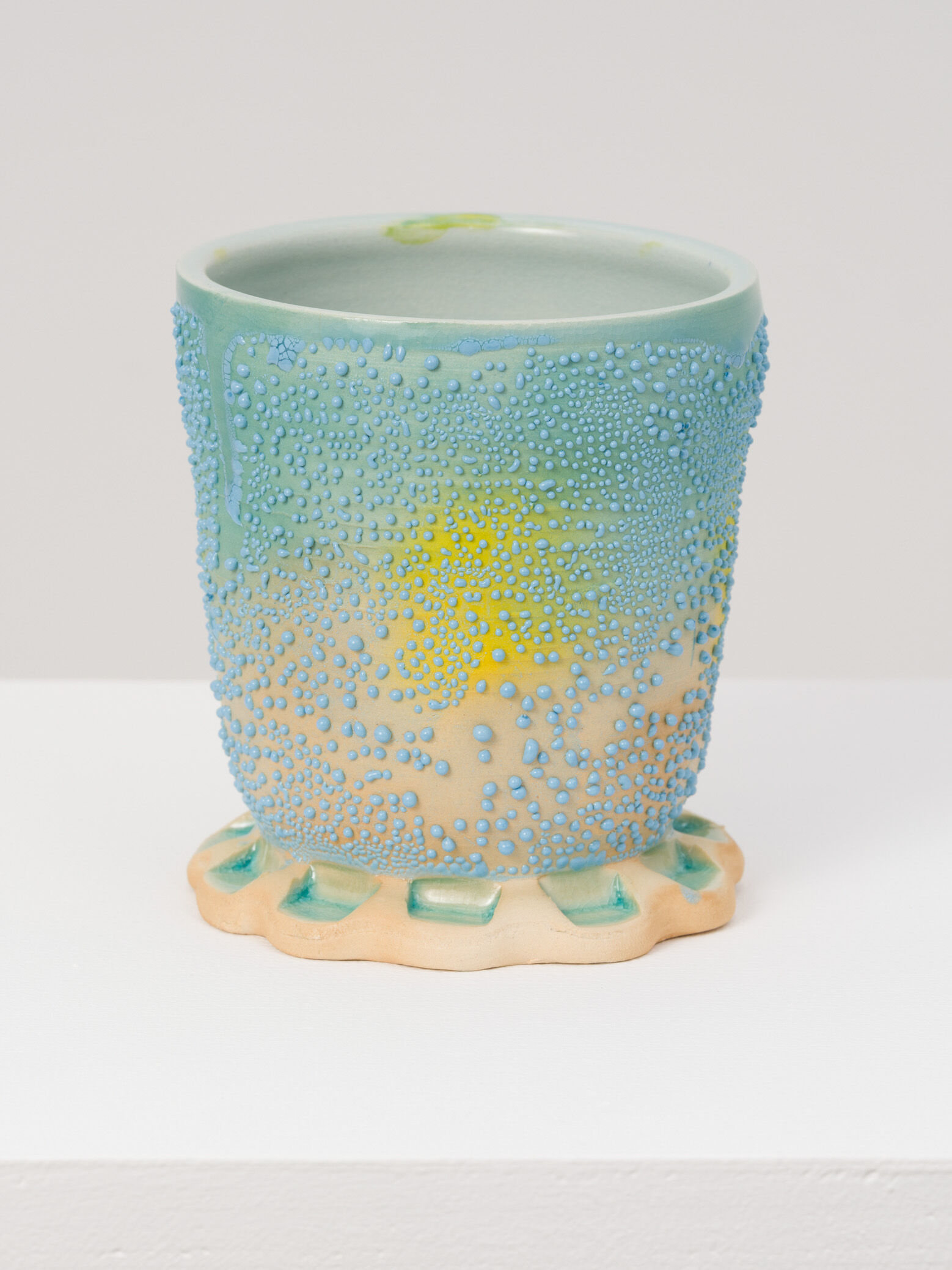 A light blue ceramic cup with a yellow spot by the artist Sharif Farrag