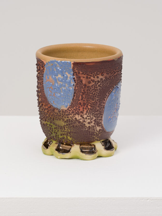 A brown ceramic cup with blue spots by the artist Sharif Farrag